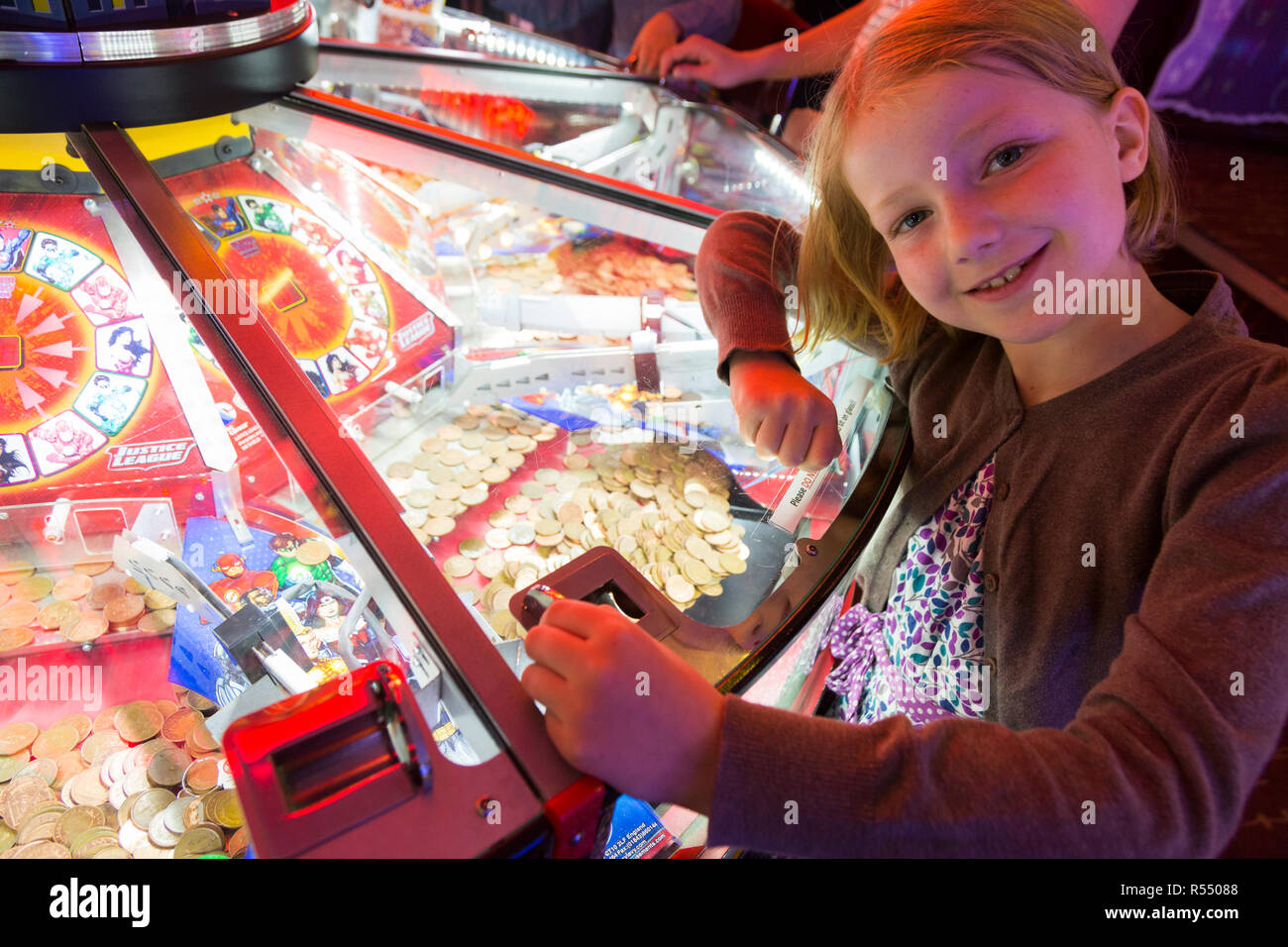 Jeune fille âgée de huit ans, l'âge de 8 ans de jouer sur un coin pusher traditionnels populaires / pièces poussant en jeu pier arcade fun house. UK. (98). Banque D'Images