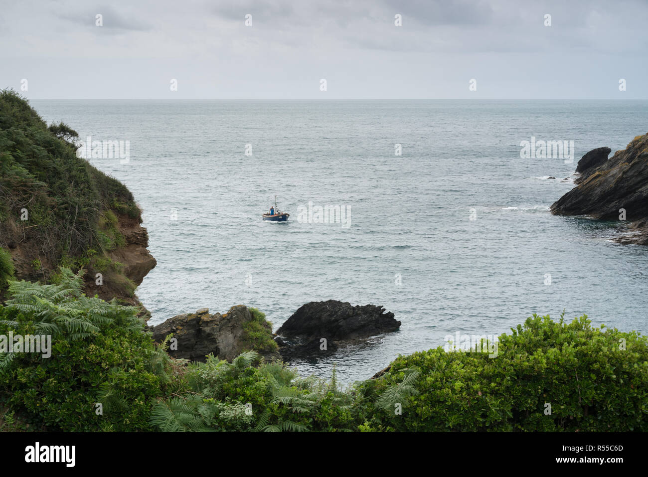 Un pêcheur solitaire pénètre dans la belle crique à Portloe à Cornwall Banque D'Images