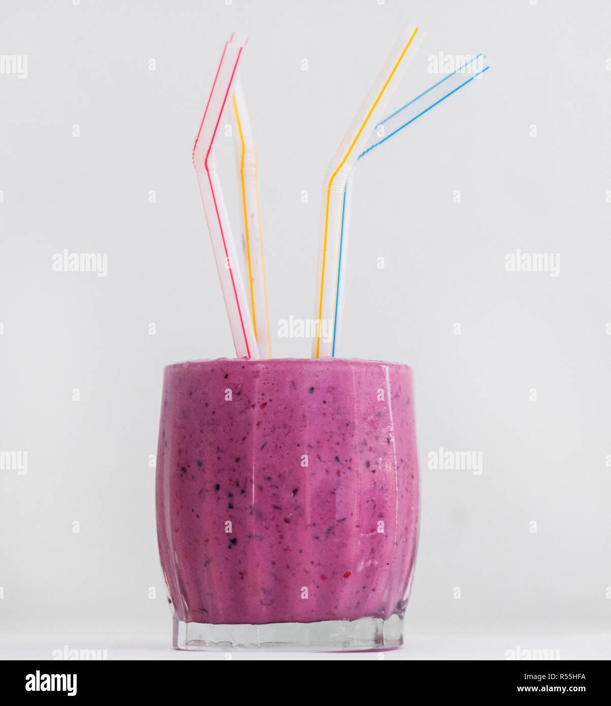 Un mélange de baies avec yaourt nature et le lait de soja est illustré dans  un verre avec une paille en plastique de couleur Photo Stock - Alamy