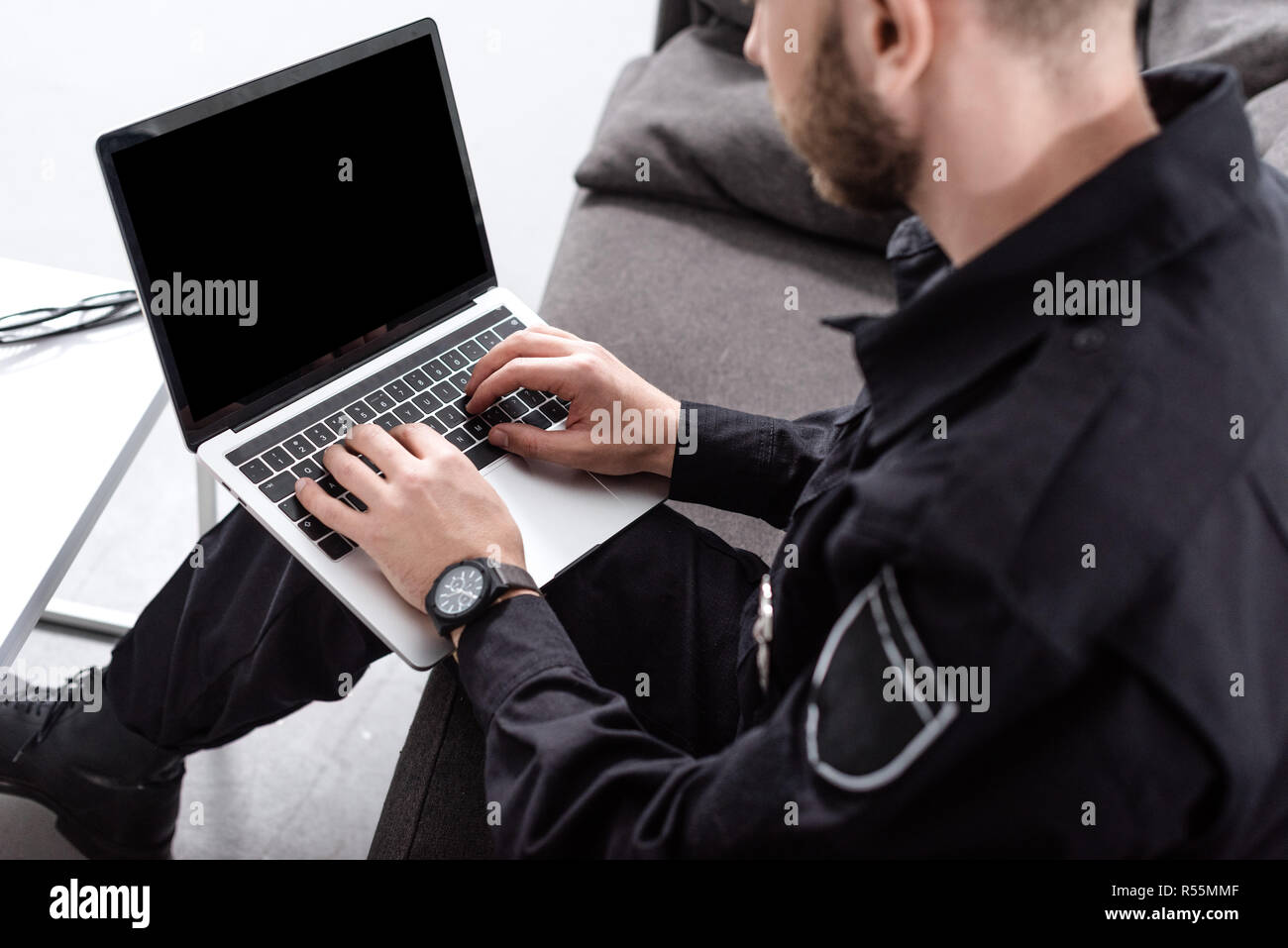 Portrait d'un agent de police assis sur la table et de la saisie sur clavier d'ordinateur portable Banque D'Images