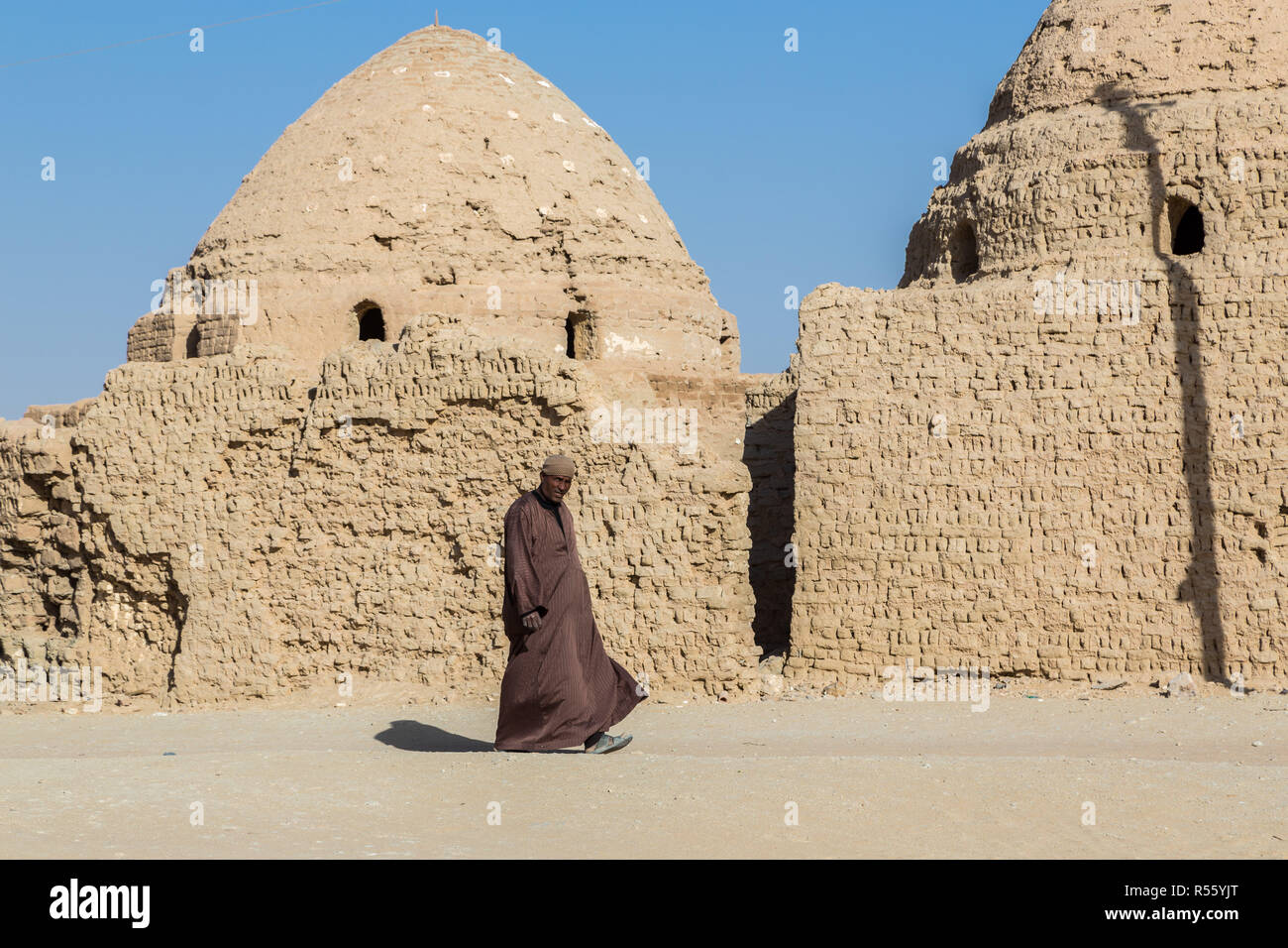 L'homme égyptien arabe locale balade habillé en robe masculine nationale thawb (thobe) par sheikh islamique ancien mausolée. Vieille ville Al Qasr, Dakhla, l'Égypte. Banque D'Images