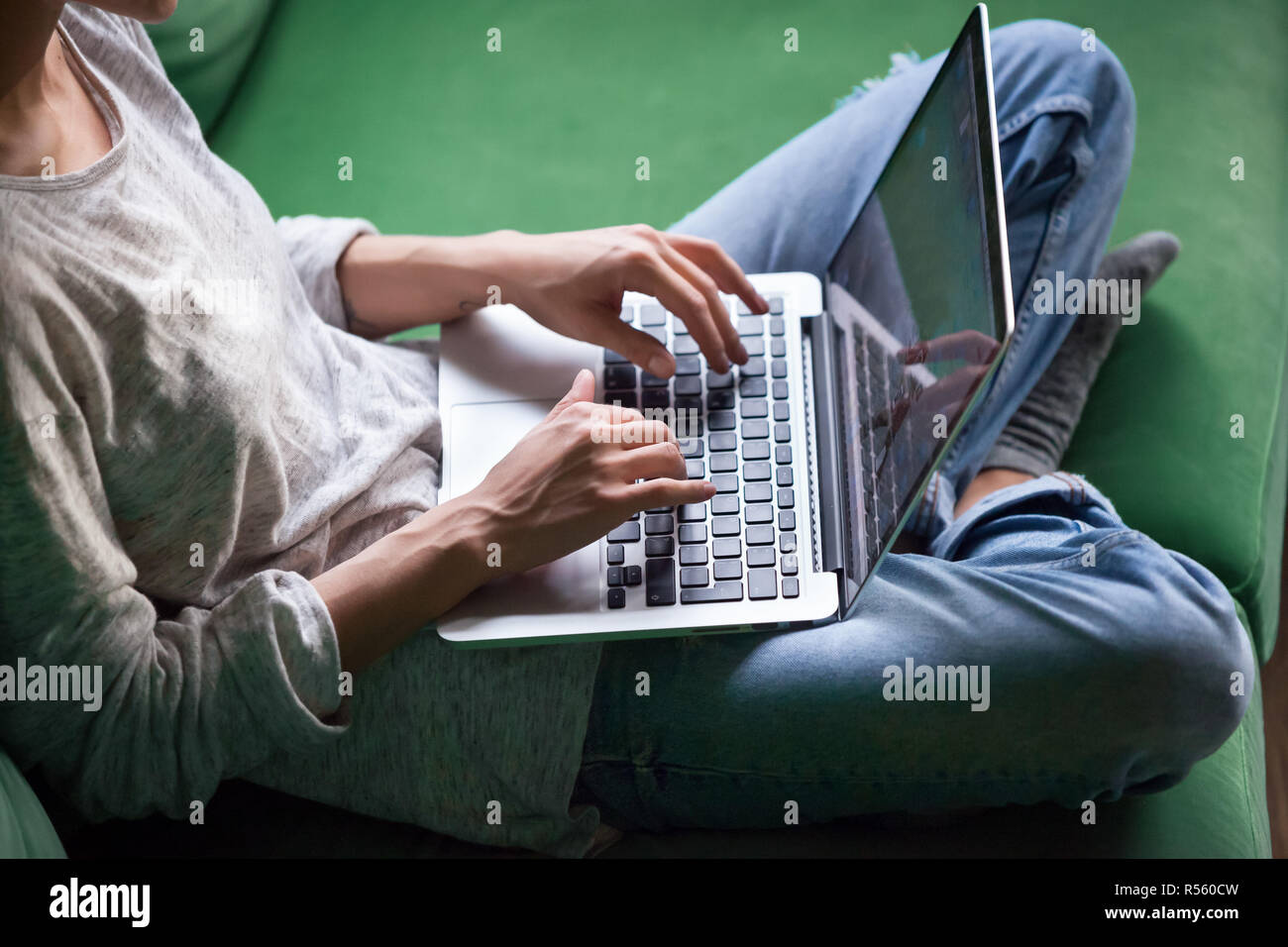 Relaxed woman sitting on sofa and using laptop Banque D'Images