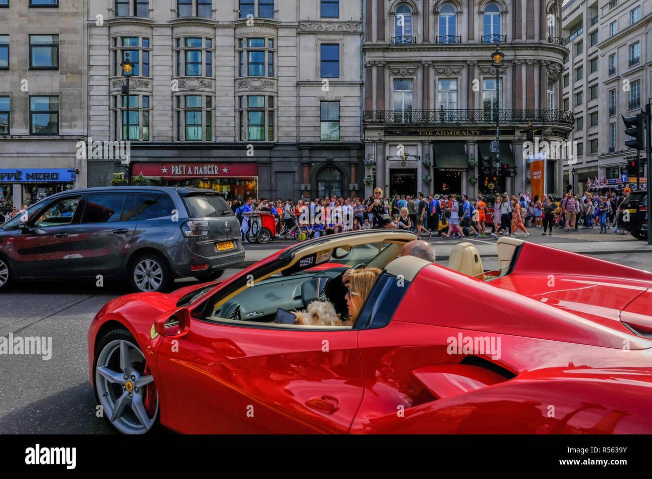 Londres, Royaume-Uni - 22 Avril 2018 : open top Ferarri rouge voiture sur la route près de Trafalgar Square. A la chaussée des foules de gens à pied. Banque D'Images