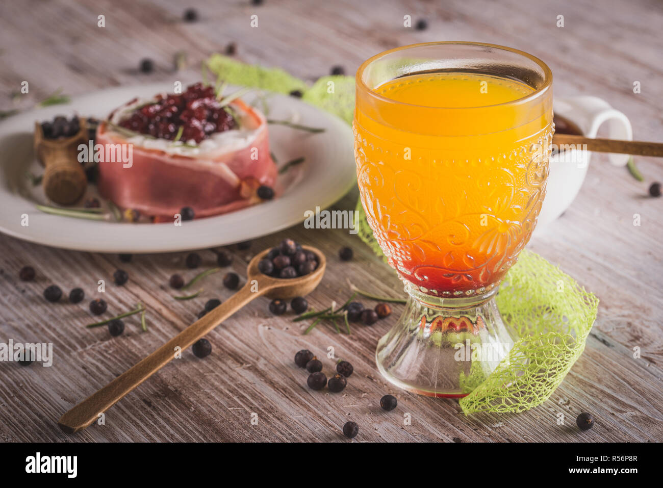 Photo horizontale du verre avec du jus d'orange qui a sirop de grenadine rouge en bas. Fromage enveloppé dans du jambon sec avec des canneberges sur le dessus est en verre avec o Banque D'Images