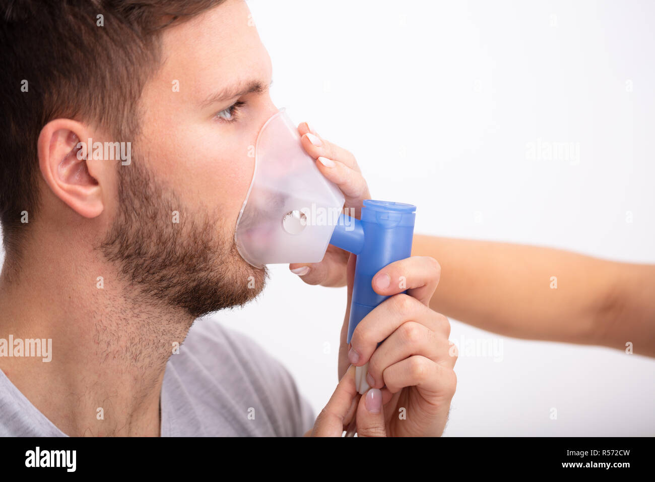 Side View of young female Doctor Holding masque à oxygène sur la bouche du patient de sexe masculin Banque D'Images
