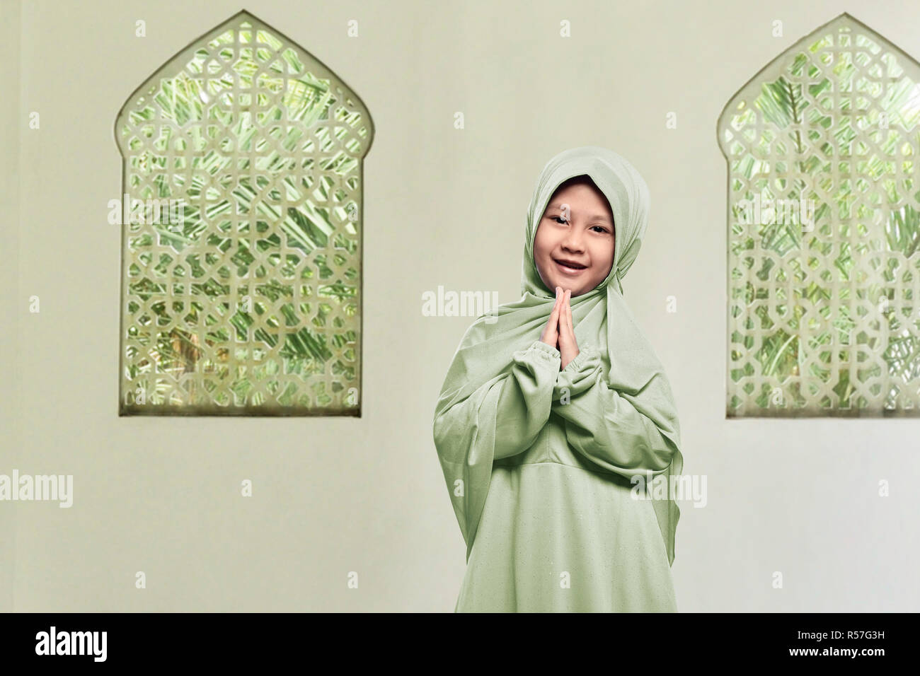 Cheerful Asian Muslim girl wearing hijab priant Banque D'Images