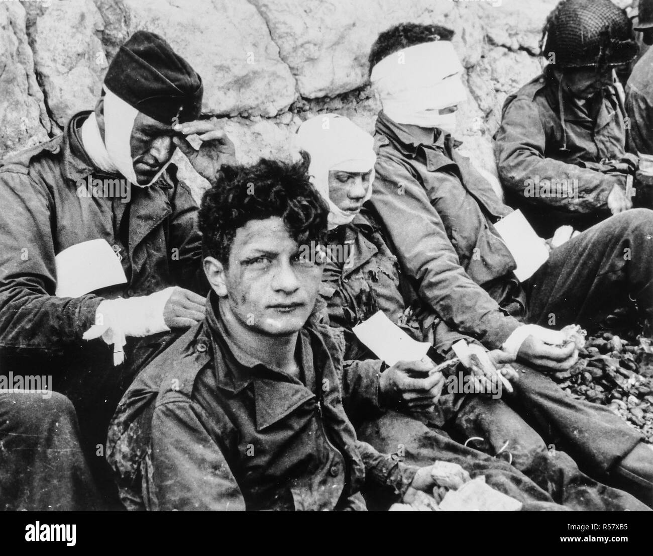 [CAPTION] l'origine un groupe de soldats américains qui, bien que blessé, d'assaut le pont et gagné la relative sécurité de Chalk cliffs à leur dos. La nourriture et les cigarettes ont été disponible pour prêter confort aux hommes. Omaha Beach, Normandie, France. 3e bat., 16ème Inf. Regt., 1re-NOUS INF. Div., Collville Sur Mer, 6 juin 1944 Banque D'Images