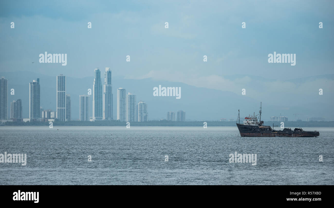 Grand tug boat près du Canal de Panama se trouve ancrée et idle dans temps chaud et humide. La ville de Panama en arrière-plan. Orage d'approches. Banque D'Images