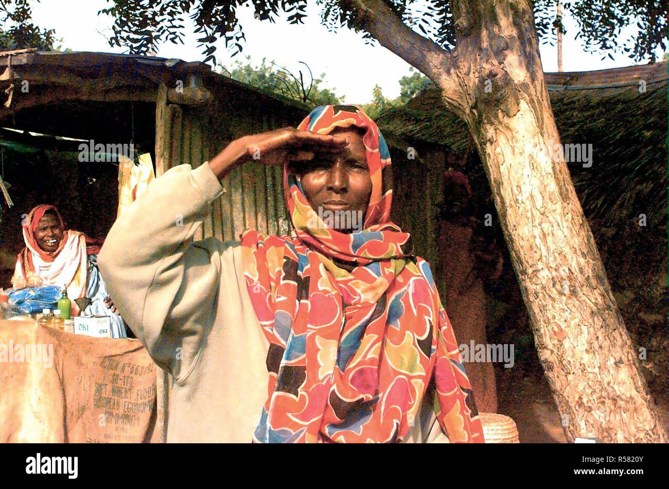 1993 - Tout droit tiré d'une Somalienne de la taille qu'elle rend un hommage à montrer son soutien aux forces américaines (non illustré) en Somalie, dans le cadre de l'opération continuent d'espoir. La photographie a été prise dans le secteur du marché de Kismayo, en Somalie. Une autre femme somalienne est vue à la gauche dans l'arrière-plan et elle rit. Banque D'Images