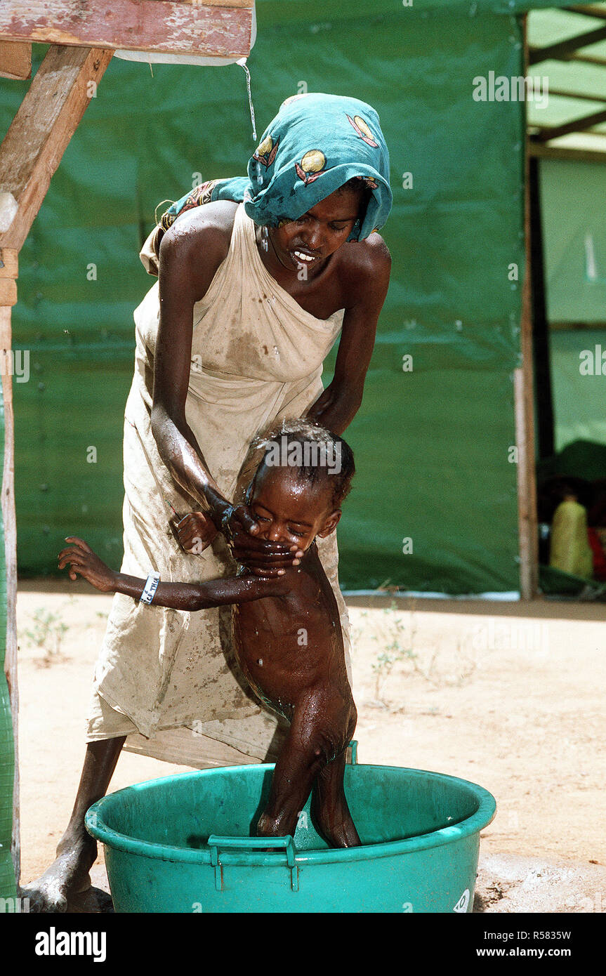 1993 - Une mère somalienne baigne son bébé dans un poste de secours mis en place lors de l'Opération Restore Hope les efforts de secours. Banque D'Images