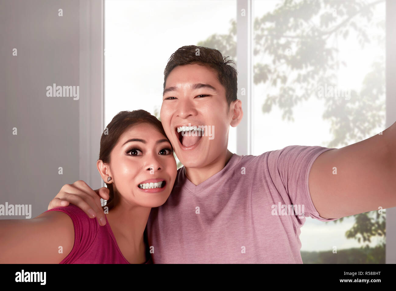 Young Asian couple taking photo selfies intérieur avec de grandes fenêtres Banque D'Images