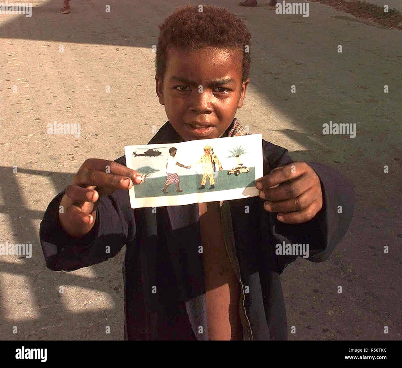 1993 - Un jeune garçon somalien à tenir l'une des brochures d'OPSPSY jusqu'à l'appareil photo. Le dépliant est un dessin à la main un Somalien homme serrant la main d'un membre des Forces canadiennes. L'établissement transmet à la population somalienne qui essayent d'aider à mettre fin à leur souffrance et n'est ici que leurs amis. Banque D'Images