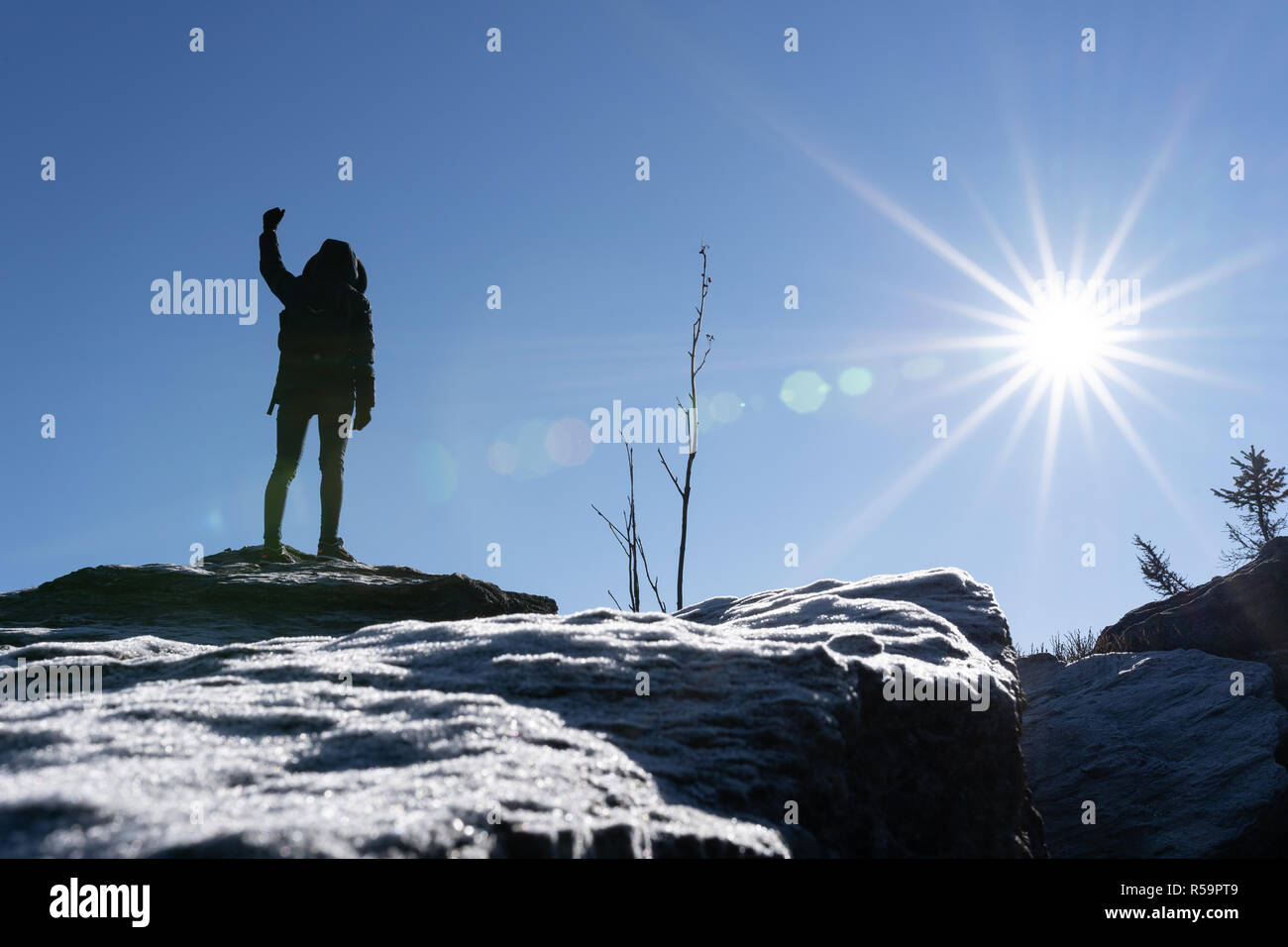 Cheering woman hiker bras ouverts au sommet de montagne avec de lourdes rétroéclairé et lens-flare crystalls glace au premier plan. Banque D'Images
