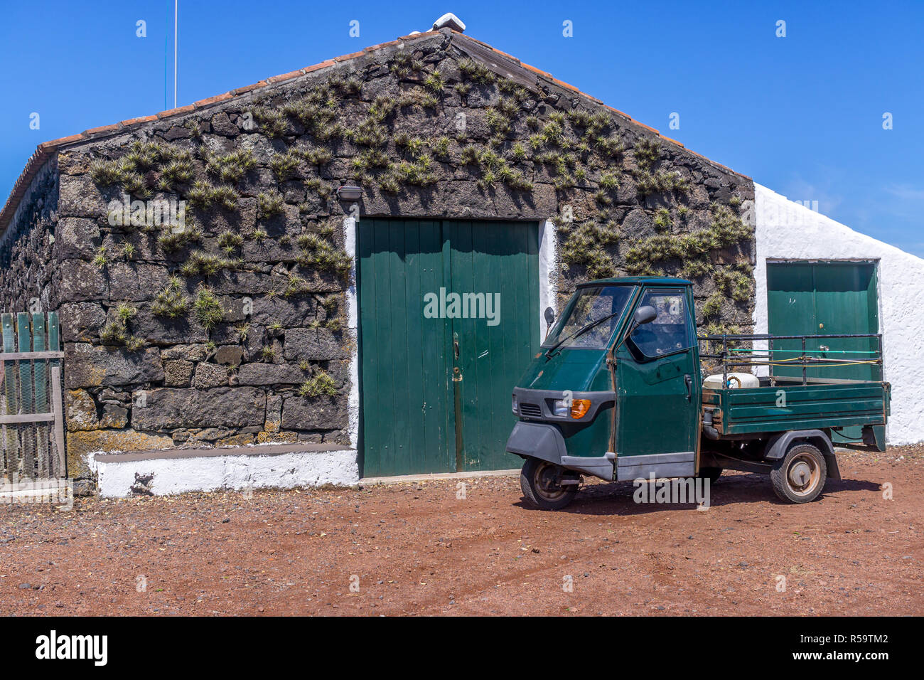 Bâtiment utilisé pour le stockage et la fabrication du vin avec un petit, ancien utilitaire véhicule garé en face. L'île de Pico, Açores, Portugal Banque D'Images