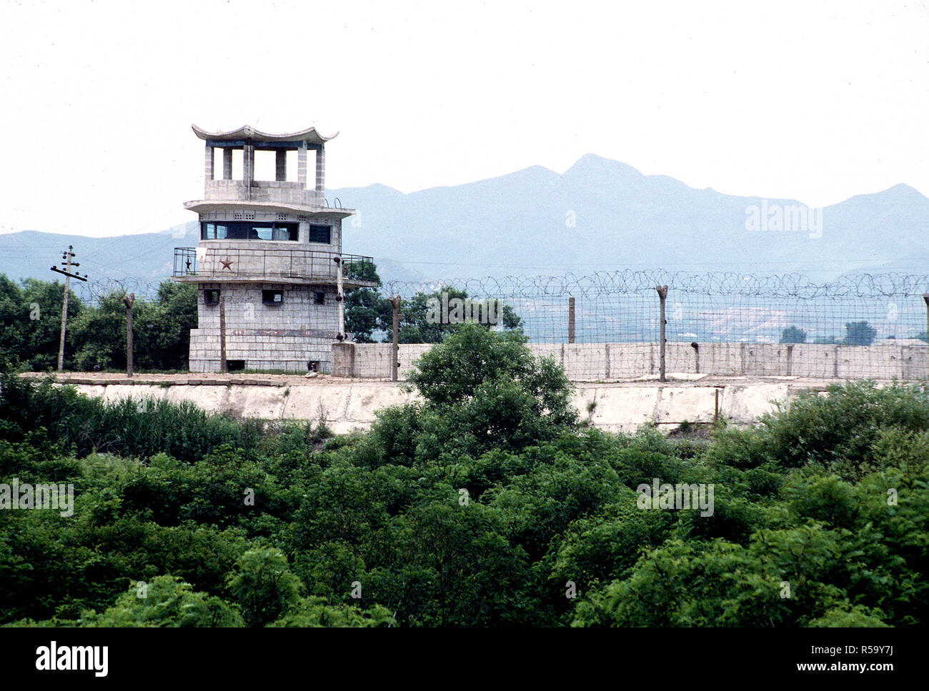 Vue sur le mur de béton et de barbelés séparant la Corée du Sud de la Corée du Nord, Kijong-Dong "propagande Village'. Notez l'étoile rouge communiste situé sur la tour de garde. La ligne de démarcation militaire (LDM) passe juste devant le mur. Banque D'Images