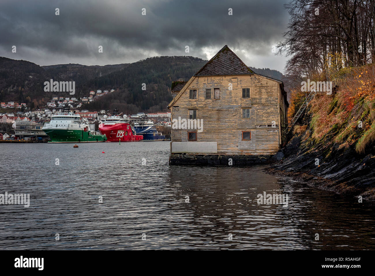 Ancien entrepôt debout à côte raide en décor de l'automne. En arrière-plan les navires de ravitaillement en mer et l'entrée au port 08 Bergens Banque D'Images
