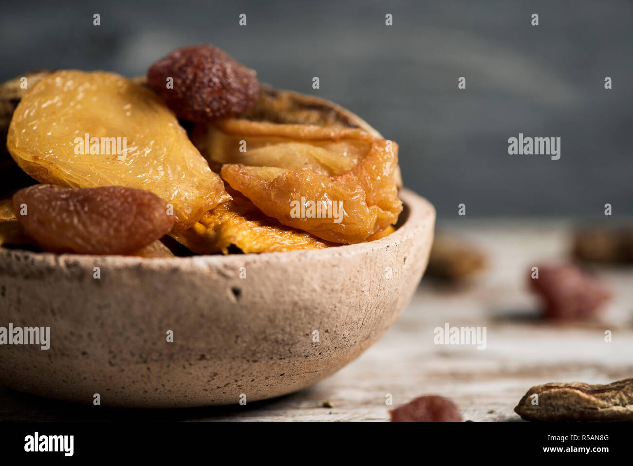 Libre d'un bol en terre cuite rustique rempli d'un assortiment de fruits secs, tels que poire, pêche, banane, fraise, Pomme, abricot ou sur une table en bois Banque D'Images