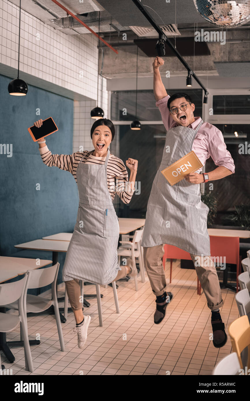 Couple jumping élevé alors que l'entreprise familiale d'ouverture incroyable sentiment Banque D'Images