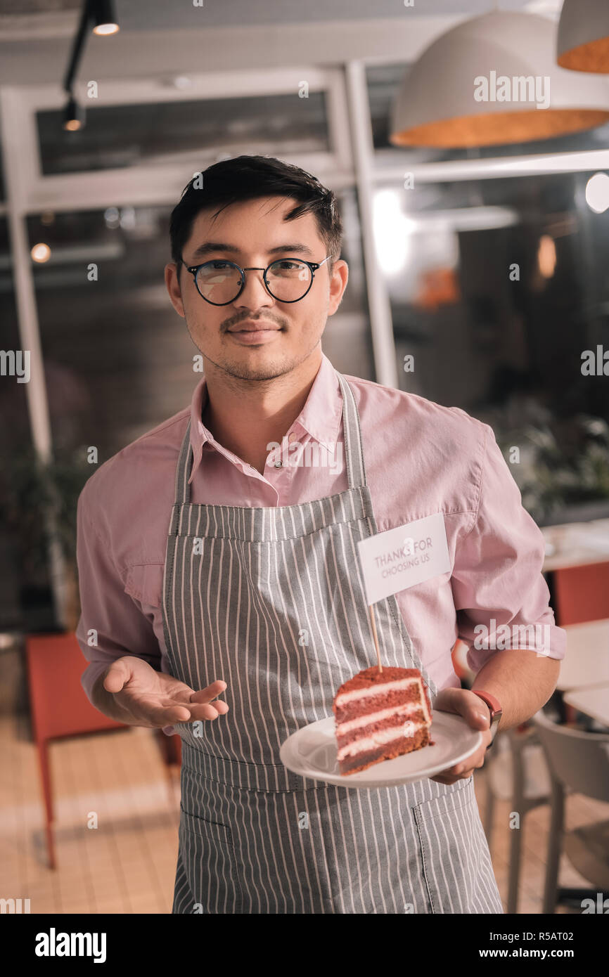 Jeune entrepreneur holding délicieux gâteau on white plate forme son cafe Banque D'Images