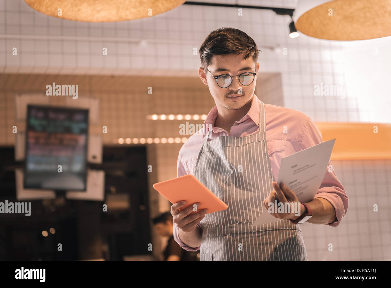 Homme portant un tablier à rayures entrepreneur de son restaurant menu holding Banque D'Images