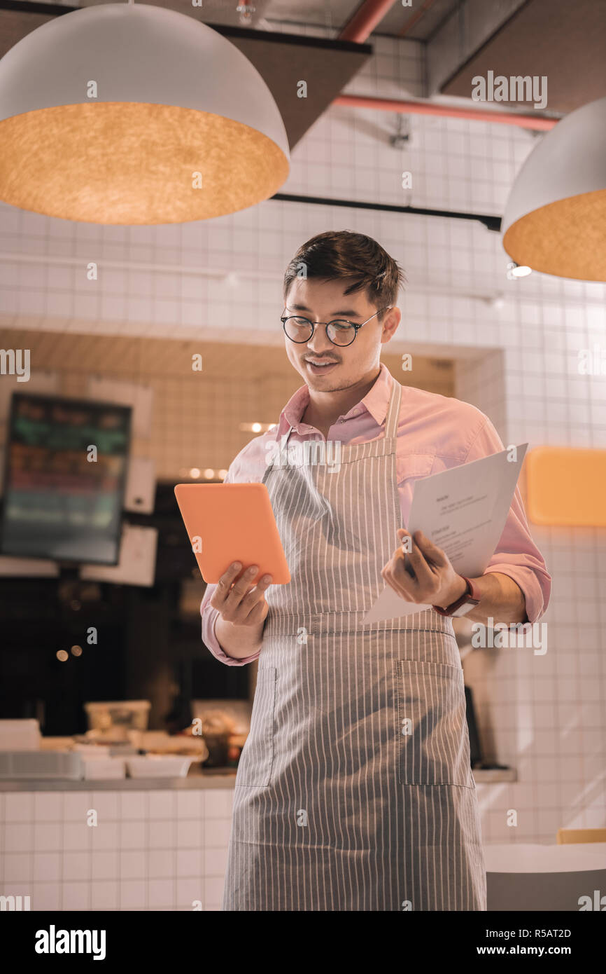 Bel homme portant des lunettes à la recherche de son menu à la cafétéria Banque D'Images