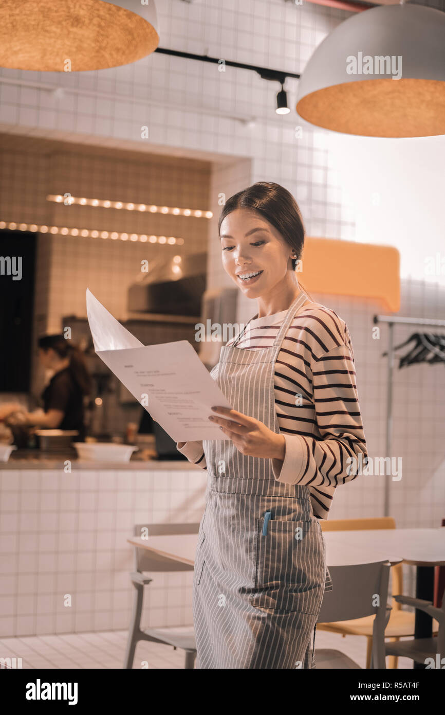 Transmission de la femme à la recherche de son menu à la cafétéria peu Banque D'Images
