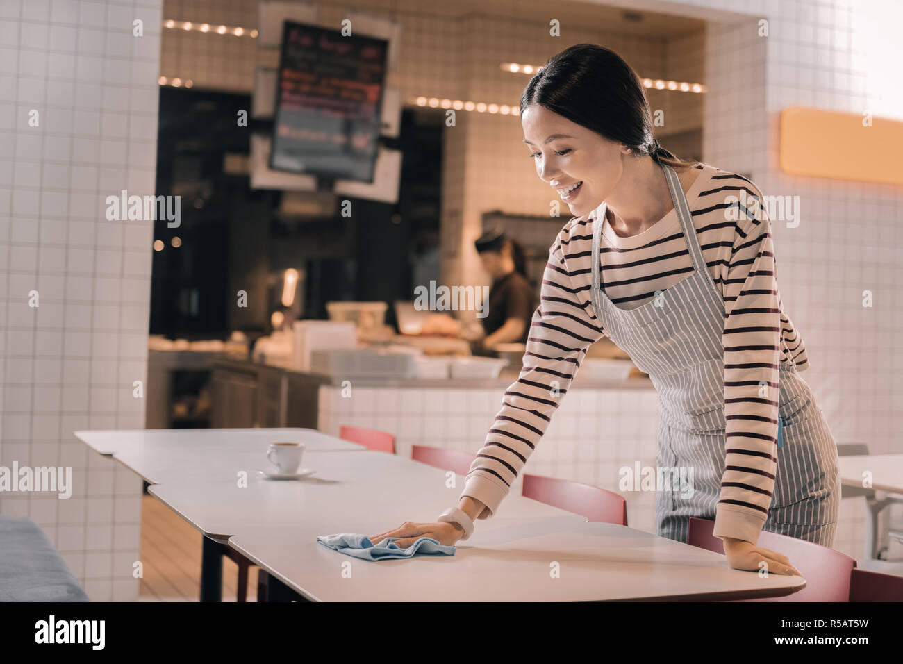 Serveuse professionnel diligent nettoyer la table le matin Banque D'Images