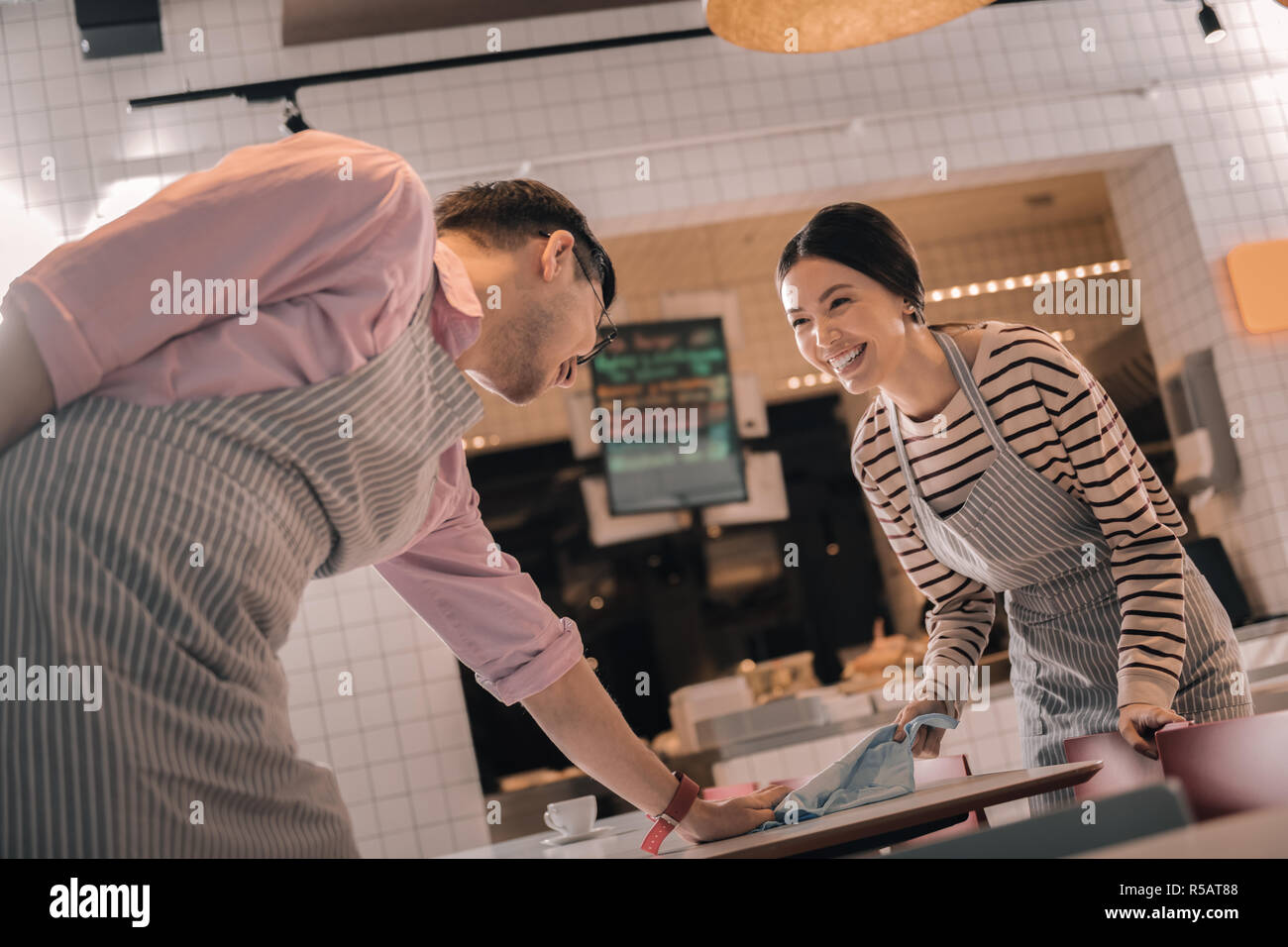 Deux serveurs de rire tout en nettoyant l'ensemble de la table Banque D'Images