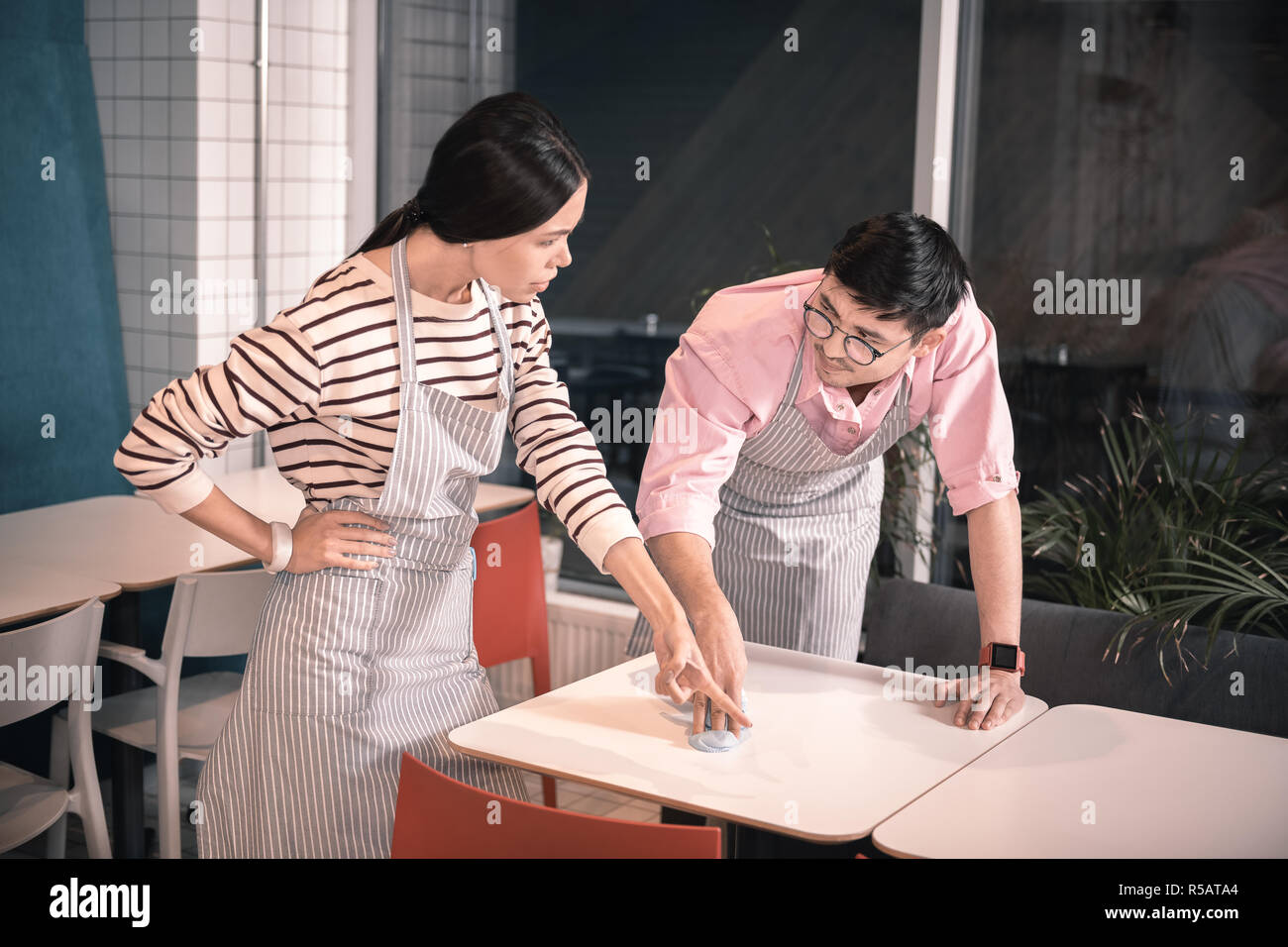Dark-haired propriétaire de restaurant réprimandes jeune garçon inexpérimenté Banque D'Images