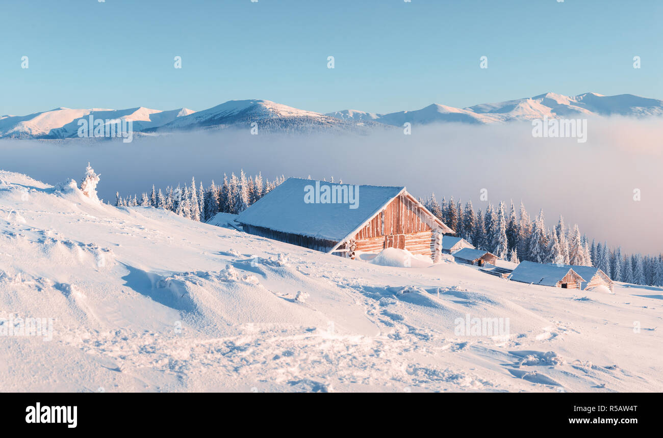 Paysage d'hiver fantastique avec maison en bois dans les montagnes enneigées. Concept de vacances de Noël Banque D'Images