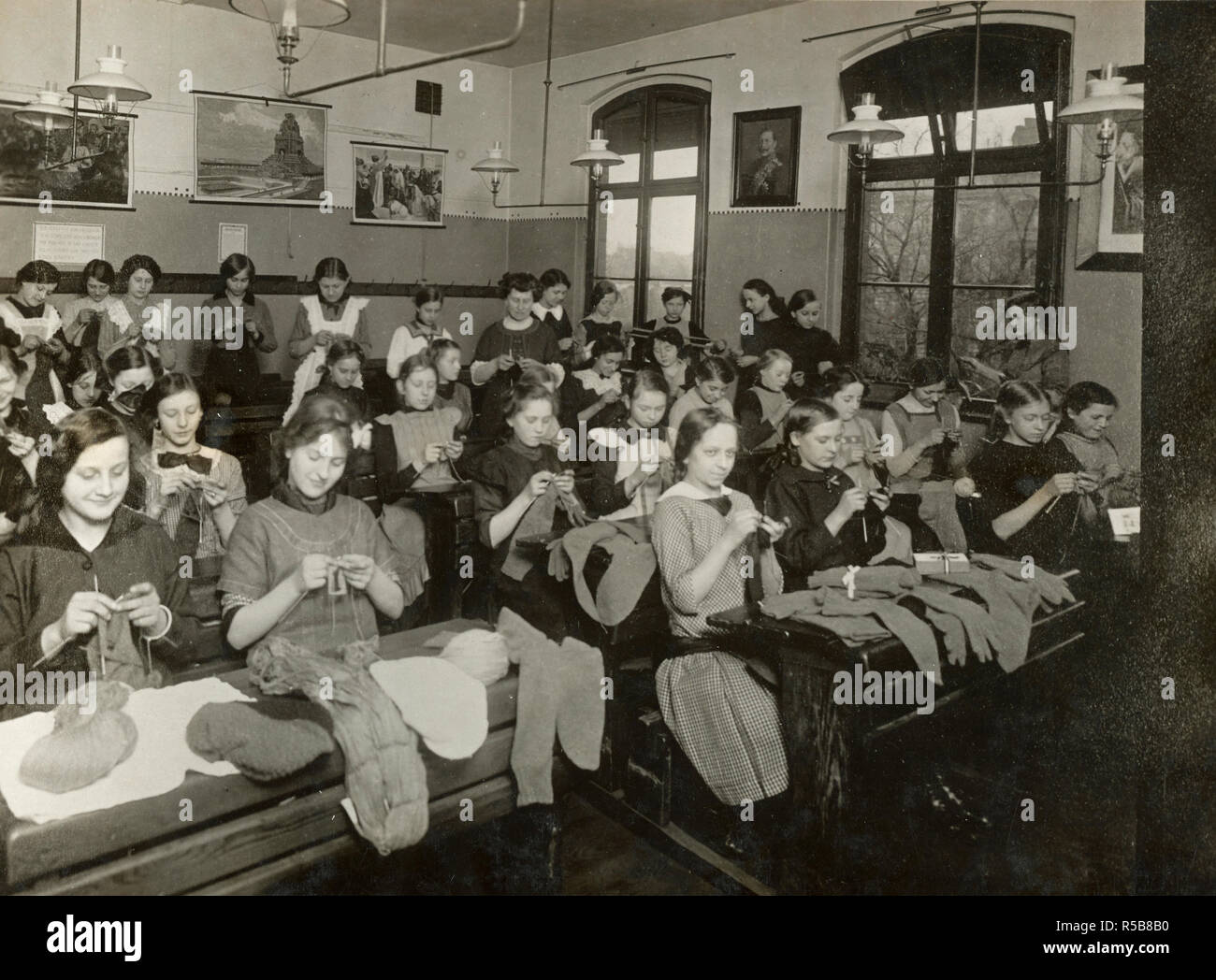Les enfants de l'école dans les cours de sciences apprendre à tricoter des chaussettes pour les soldats sur le terrain. Bonne photo de propagande. Remarque Kaiser entre les sujets bibliques sur le mur ca. 1918 Banque D'Images