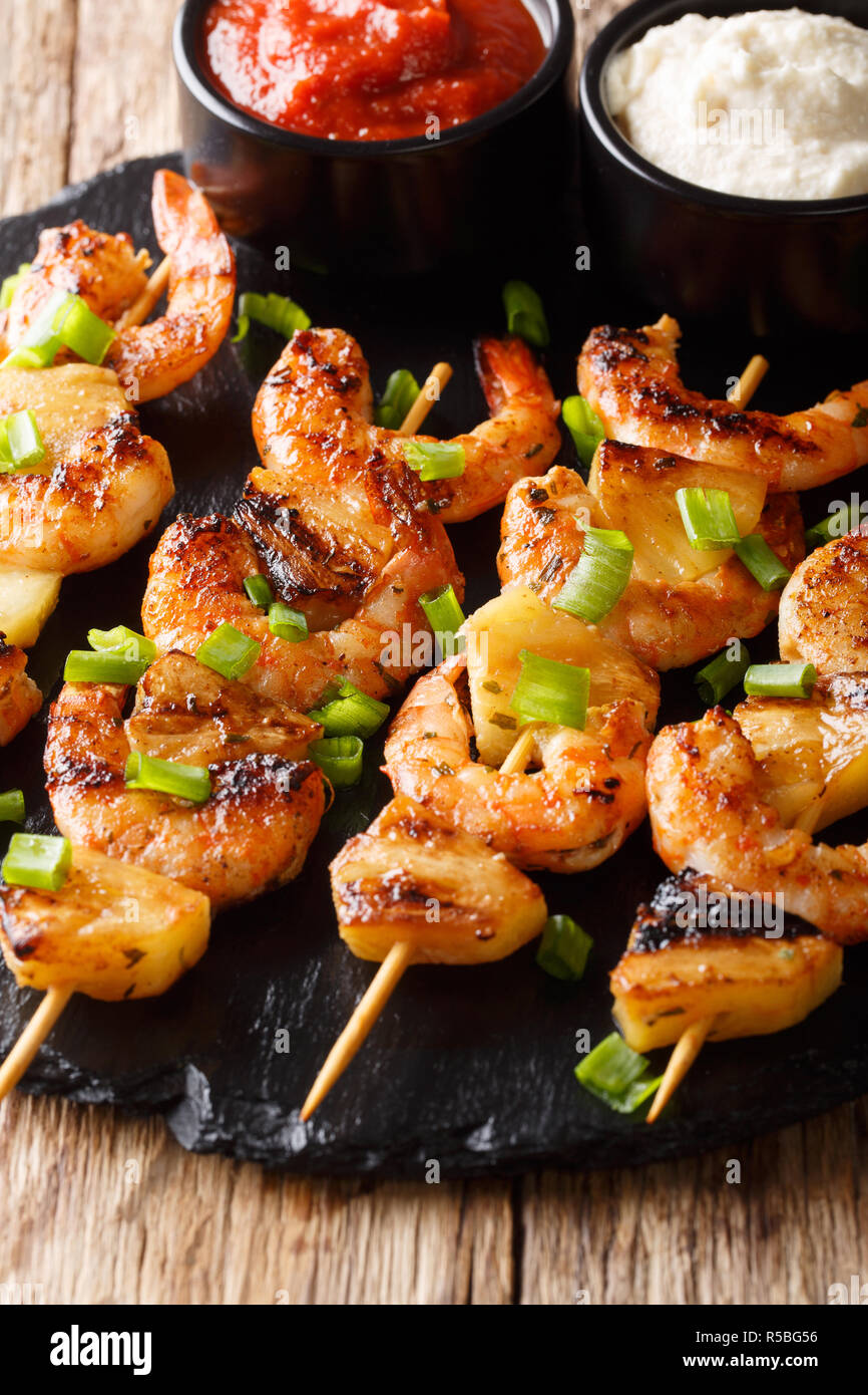 Brochette de crevettes épicées avec de l'ananas servi avec deux sauces close-up sur la table verticale. Banque D'Images