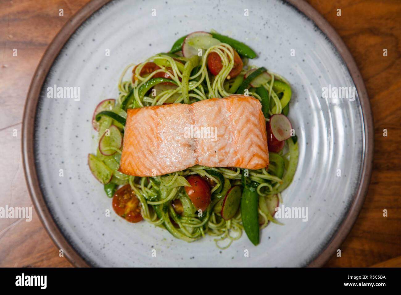 Saumon à la vapeur sur un lit de salade de nouilles et de courgettes Banque D'Images