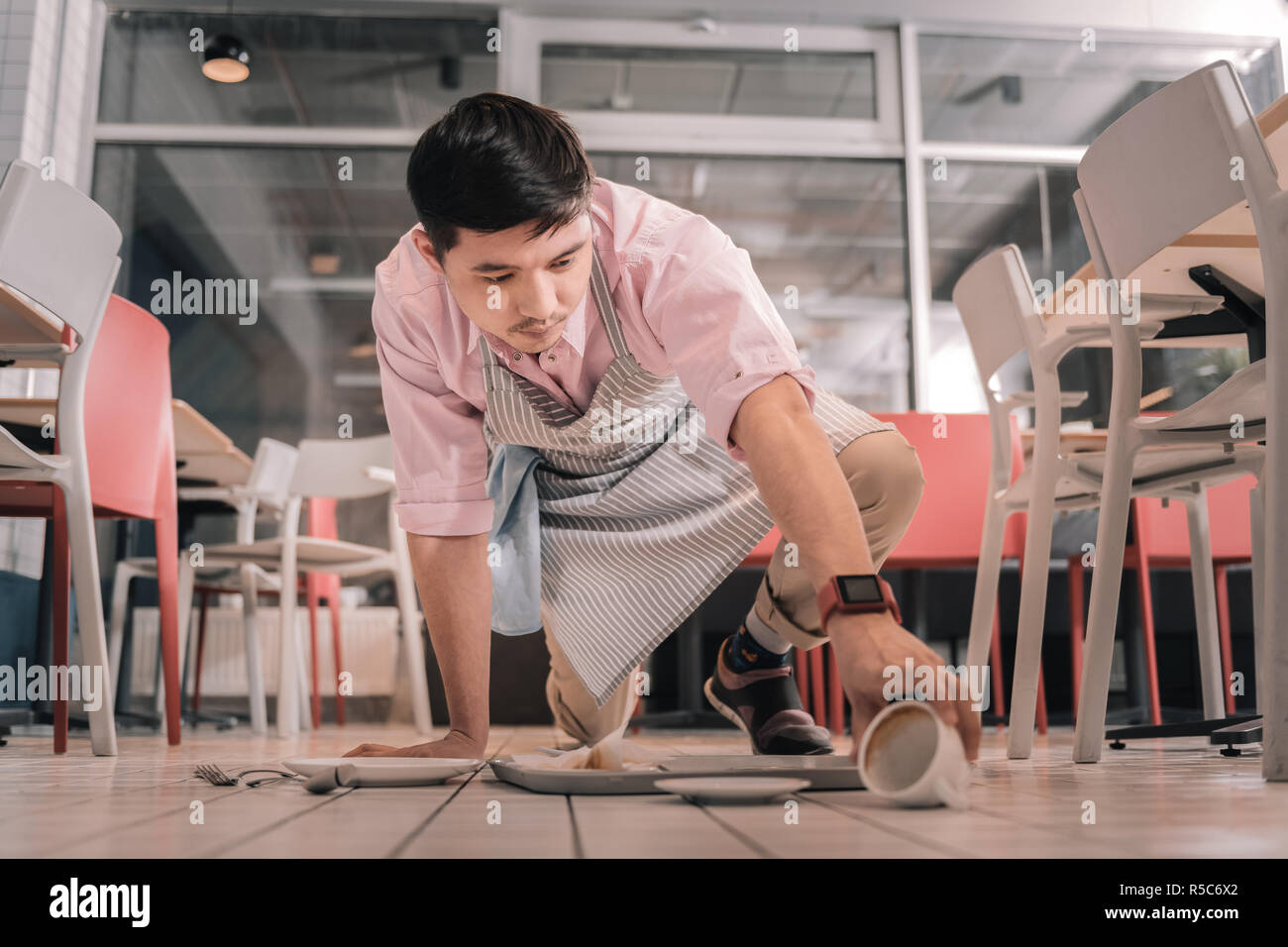 Porter un tablier à rayures serveur inattentif passant le bac avec une commande de client Banque D'Images