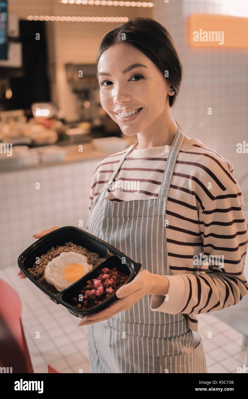 Transmission d'agréable waitress holding nice lunch box pour les clients Banque D'Images
