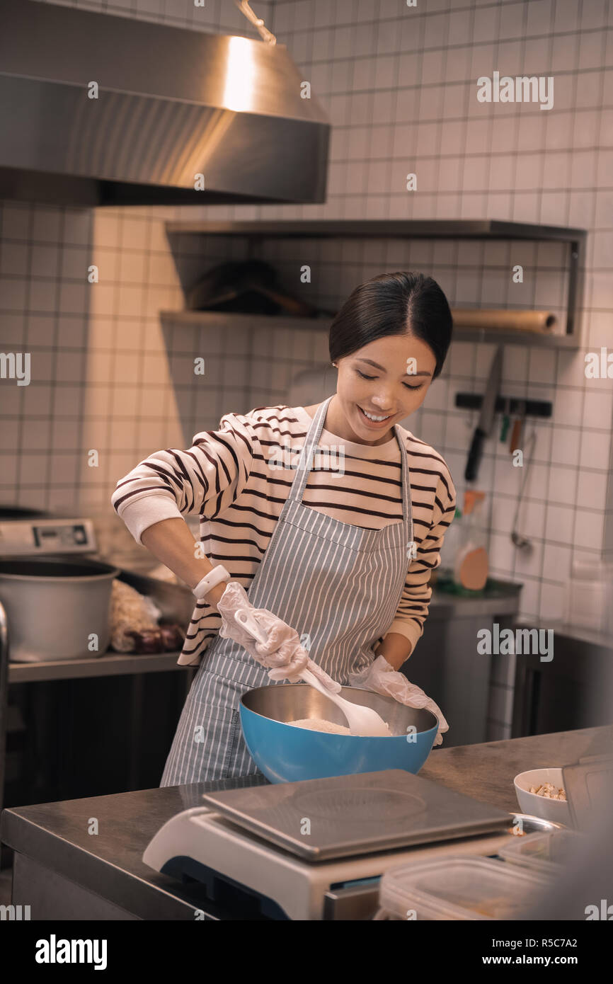 Dark-haired rayonnant de travailleur peu cafétéria la cuisson dans la cuisine Banque D'Images