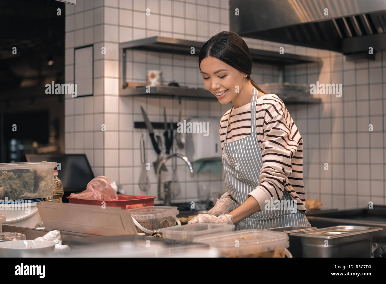 Dark-haired propriétaire de restaurant joyeuse sensation travaillant dans la cuisine Banque D'Images