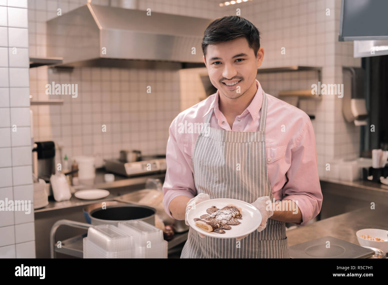 Smiling waiter holding plaque blanche avec des crêpes pour les clients Banque D'Images