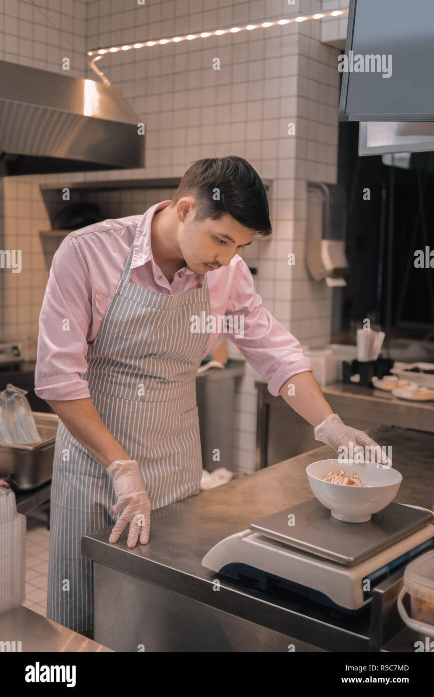 Dark-haired chef salade de mesure avant de servir de client Banque D'Images