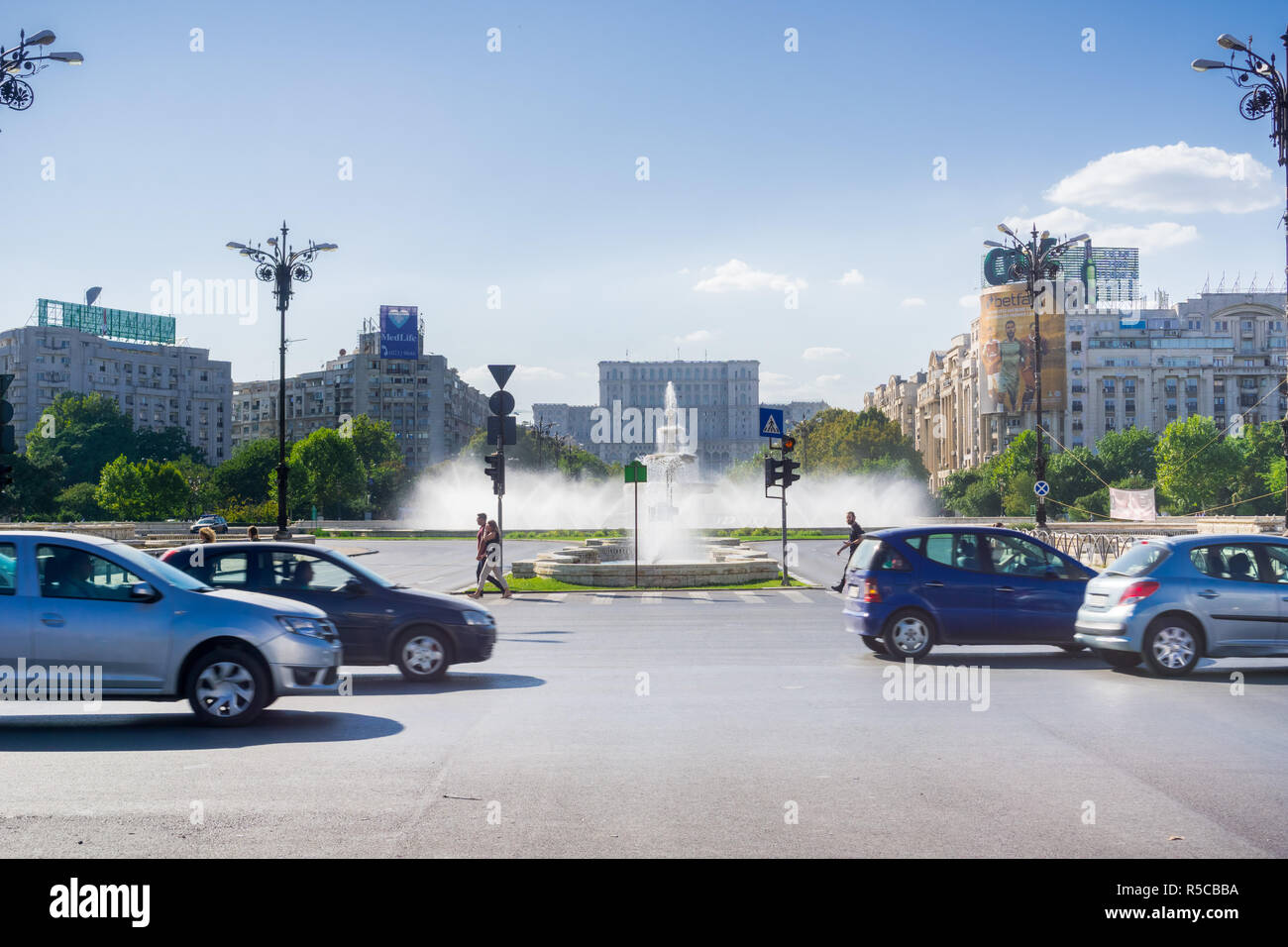 18 septembre 2017, Bucarest/Roumanie - Cars en passant par la Place Unirii, l'eau des fontaines et la Maison du Parlement à l'arrière-plan Banque D'Images