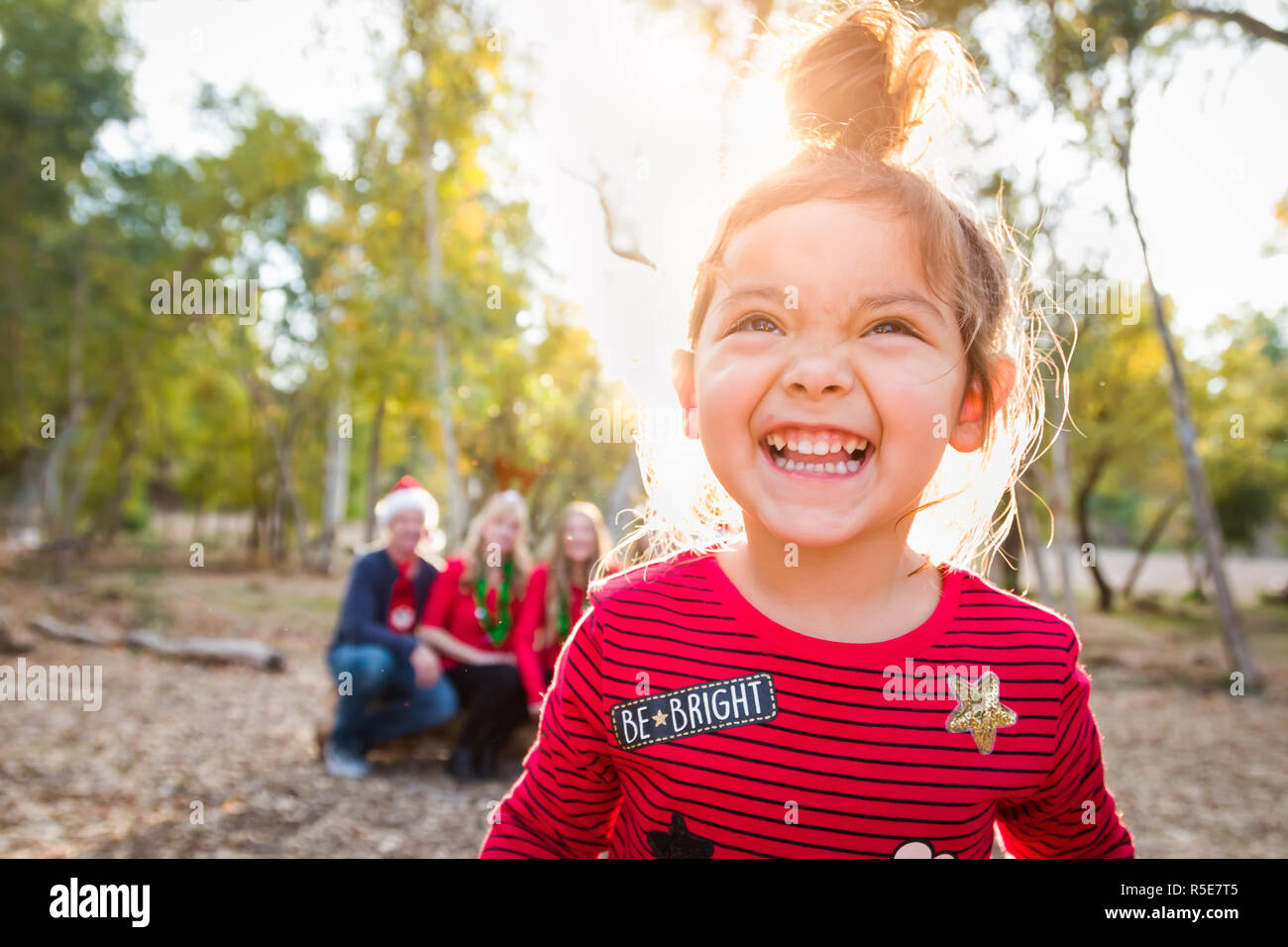 Cute Hispanic Girl Portrait de Noël avec sa famille à l'extérieur. Banque D'Images