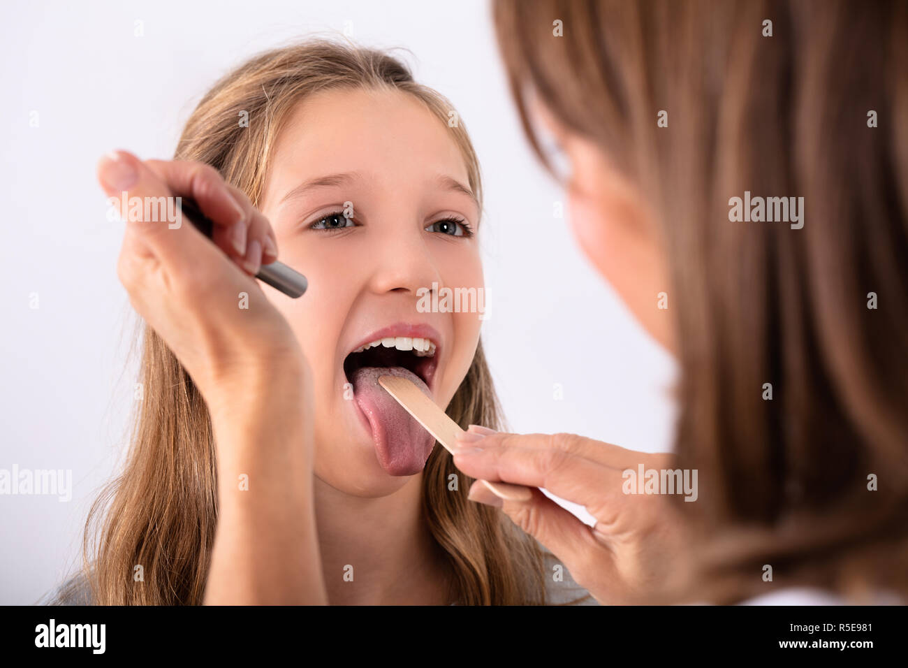 Close-up of Doctor Checking Girl's maux de gorge avec abaisse-langue Banque D'Images