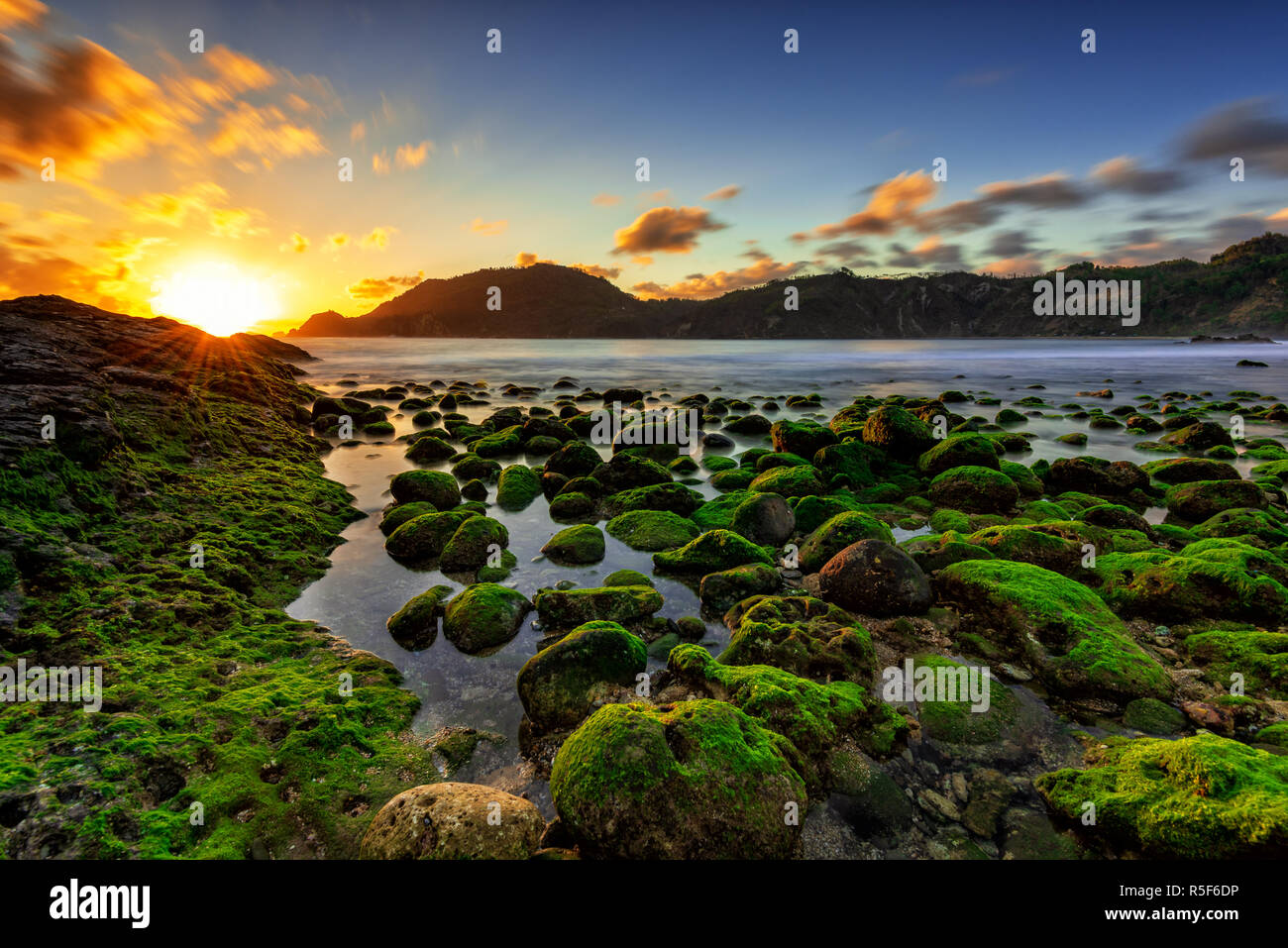 Magnifique coucher de soleil avec mousse verte au premier plan dans la plage Wediombo Jogjakarta, Indonésie Banque D'Images