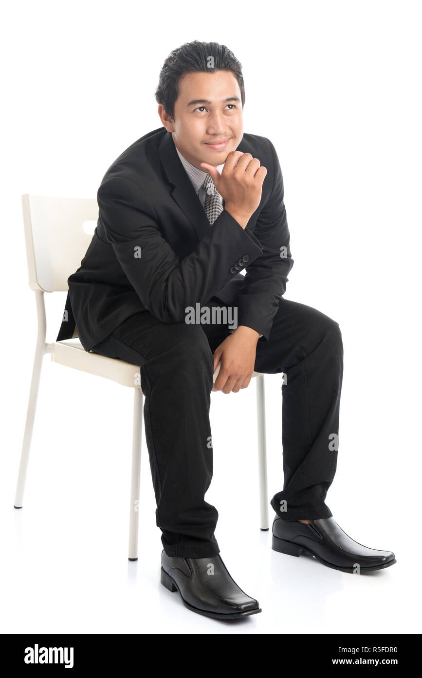 Corps complet Asian businessman sitting on chaise blanche et la pensée Banque D'Images