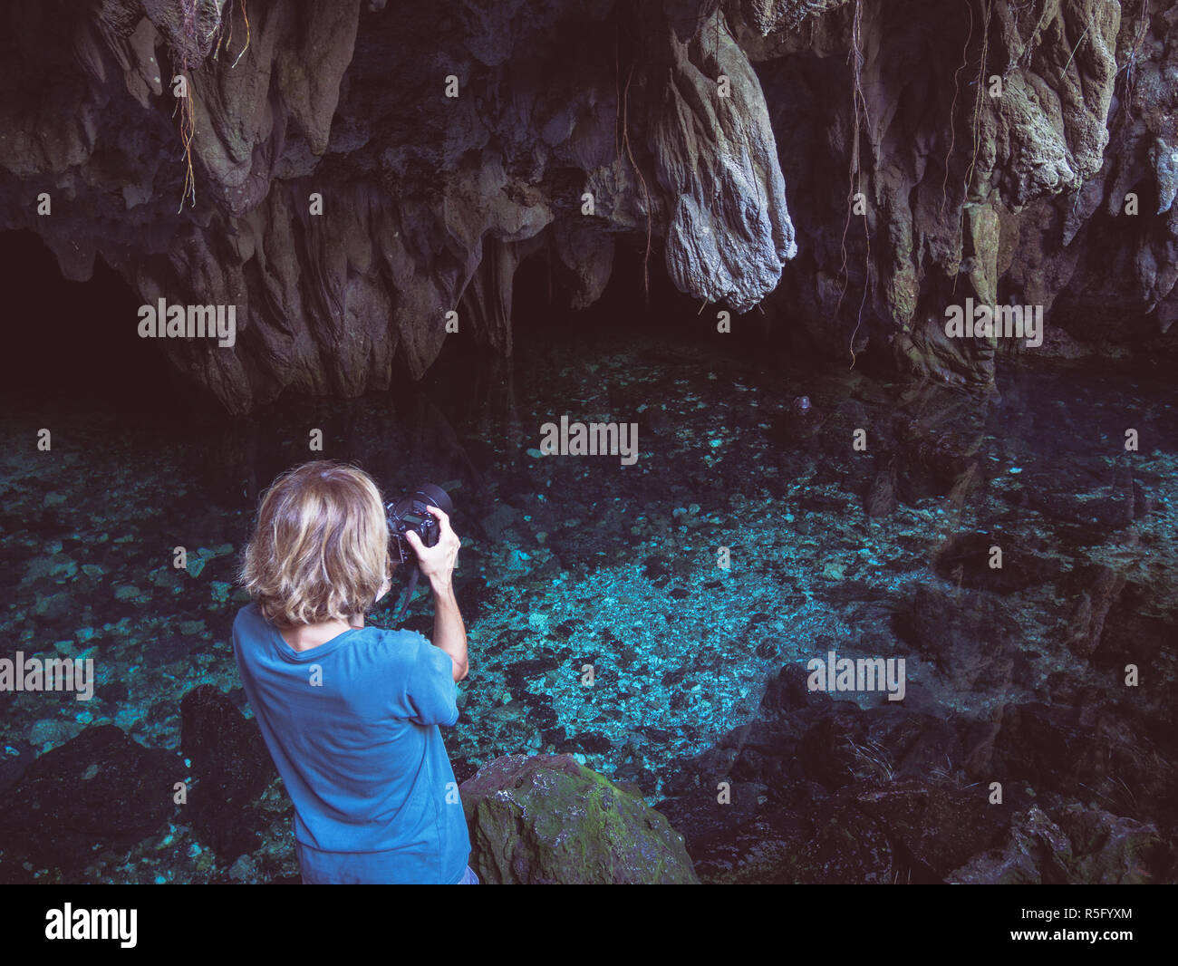Appareil photo reflex woman photographing lac naturel à l'intérieur de grotte. Reflet coloré turquoise, l'eau transparente, été aventures. Tourist Park Banque D'Images