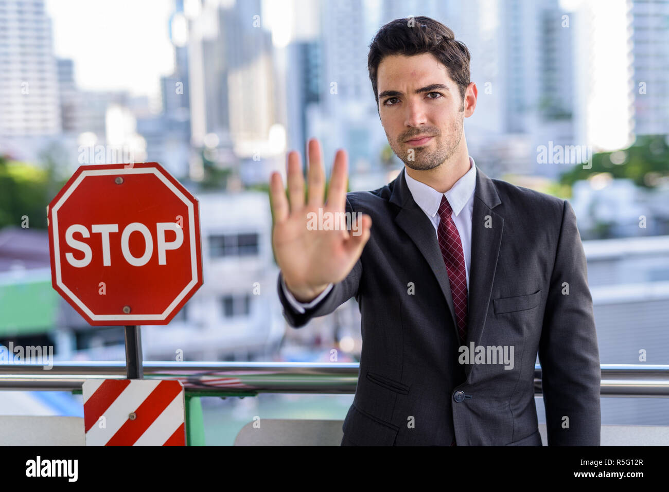 Portrait of young handsome businessman avec panneau d'arrêt Banque D'Images