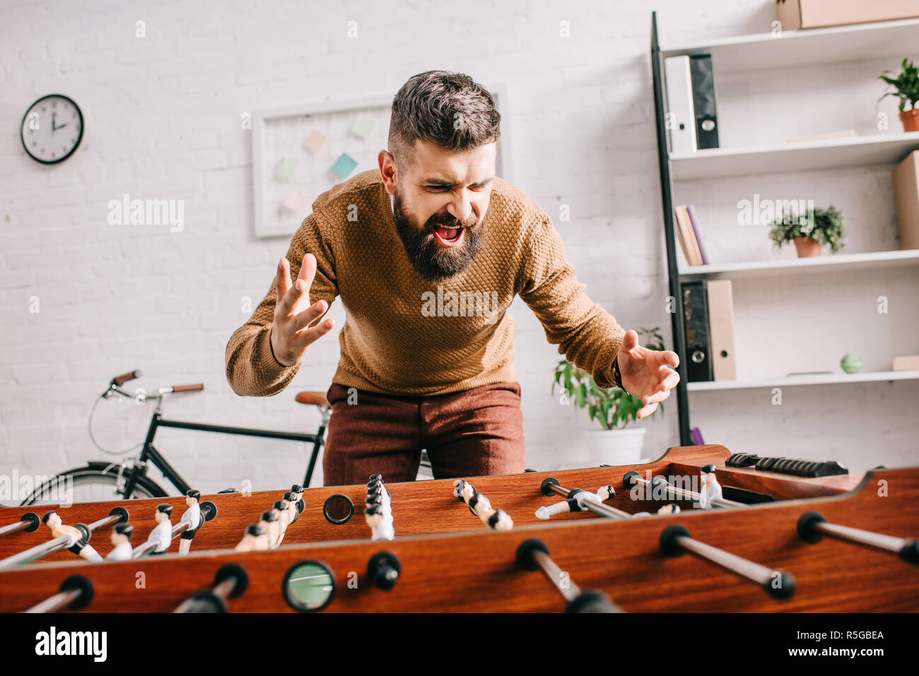 Adultes en colère man yelling et playing table football match à domicile Banque D'Images