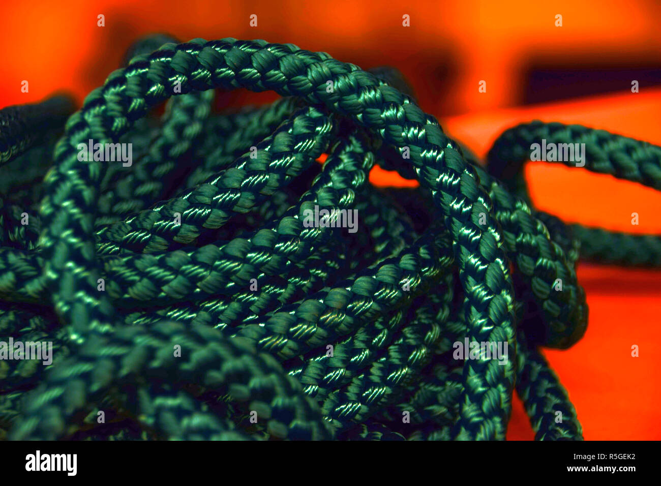 Corde synthétique fermer jusqu'en face de fond orange, nouvelle corde verte pour la macro shot voyage ou la santé ou l'industrie du sport Banque D'Images