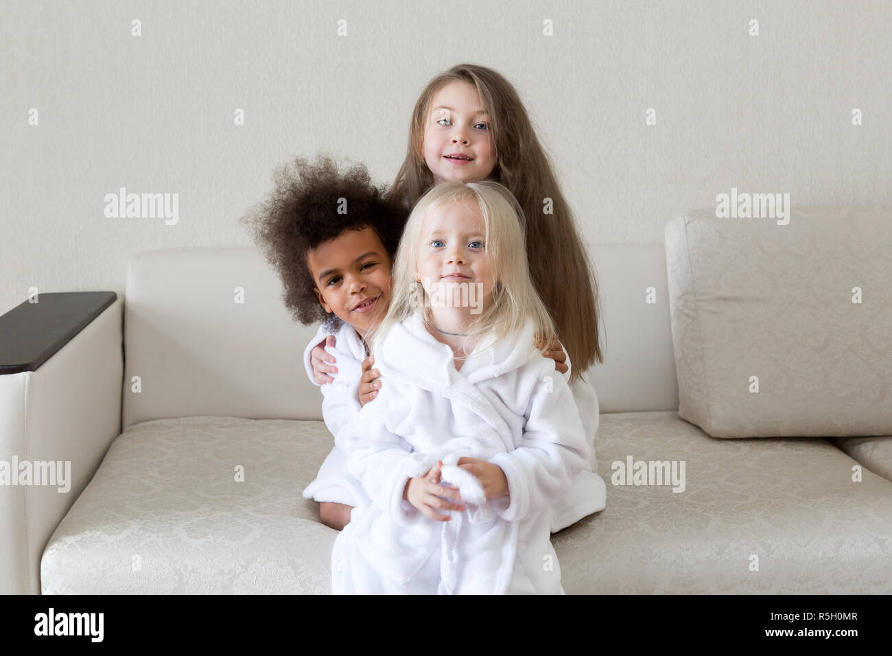 Trois magnifiques petites filles en blouse blanche après une douche ensemble blonde, brune et noire. Banque D'Images