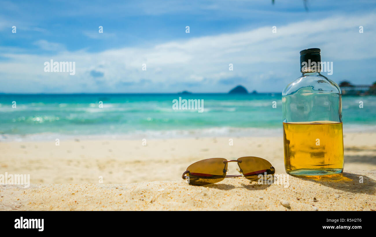Beach Party. Maison de vacances fun concept. Bouteille de rhum et des lunettes avec plage, mer en arrière-plan. Banque D'Images
